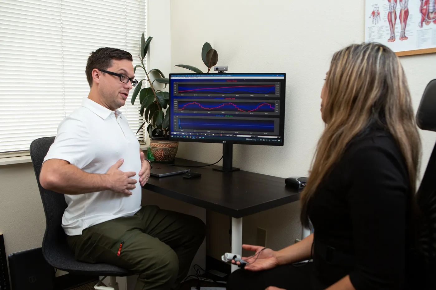 Dr. Andrew Simon guiding a patient through a biofeedback session in front of a physiological monitoring screen