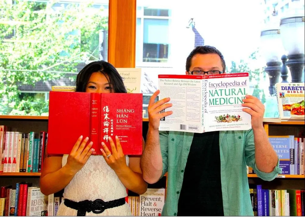 A young Dr. Andrew Simon and Dr. Phonexay Simon holding natural medicine textbooks while dreaming up their integrative clinic